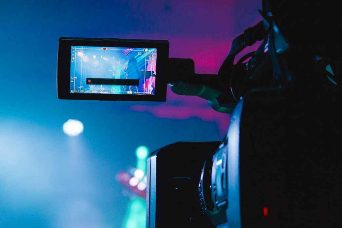 Person holding a camera with a screen displaying a colorful interface, likely at an event.